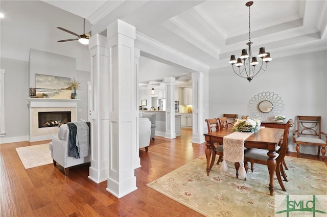 dining room with wood finished floors, a chandelier, ceiling fan, a premium fireplace, and ornamental molding