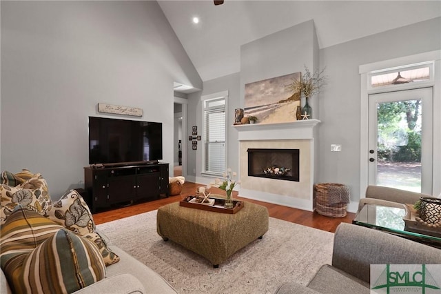 living area featuring wood finished floors, a fireplace, baseboards, recessed lighting, and high vaulted ceiling