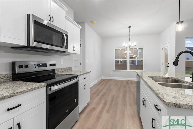 333 Crosswinds Dr, Rincon, GA 31326 - kitchen featuring appliances with stainless steel finishes, a sink, light wood-style floors, a chandelier, and white cabinets