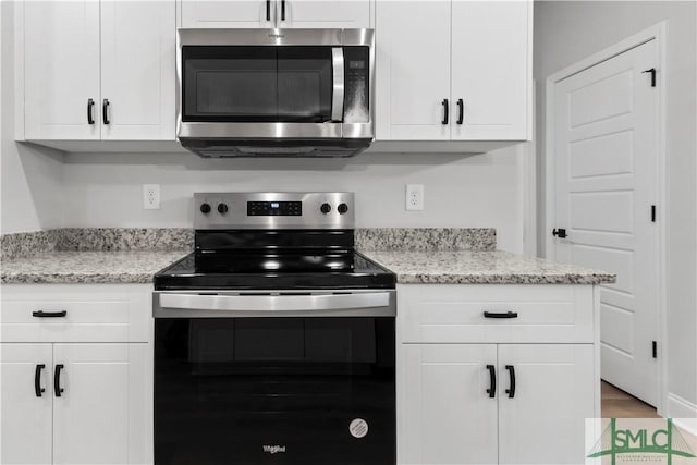 333 Crosswinds Dr, Rincon, GA 31326 - kitchen featuring stainless steel microwave, electric range, white cabinetry, light stone counters, and wood finished floors