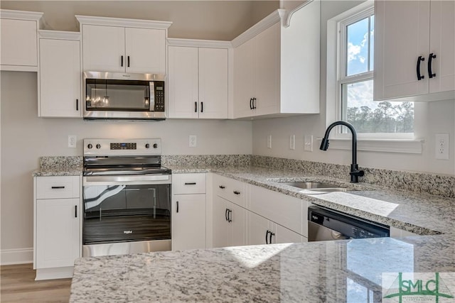 288 Timberlake Dr, Guyton, GA 31312 - kitchen with stainless steel appliances, a sink, light wood finished floors, white cabinetry, and light stone counters