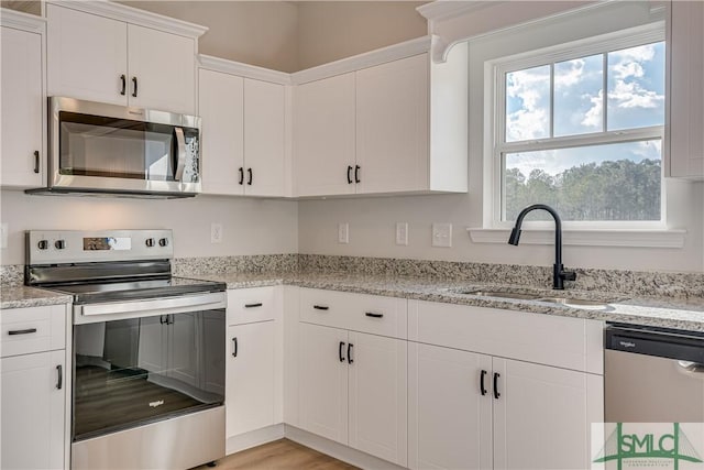 288 Timberlake Dr, Guyton, GA 31312 - kitchen with stainless steel appliances, a sink, white cabinetry, and light stone countertops