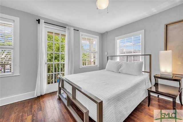 bedroom featuring multiple windows, dark wood-type flooring, baseboards, and a ceiling fan