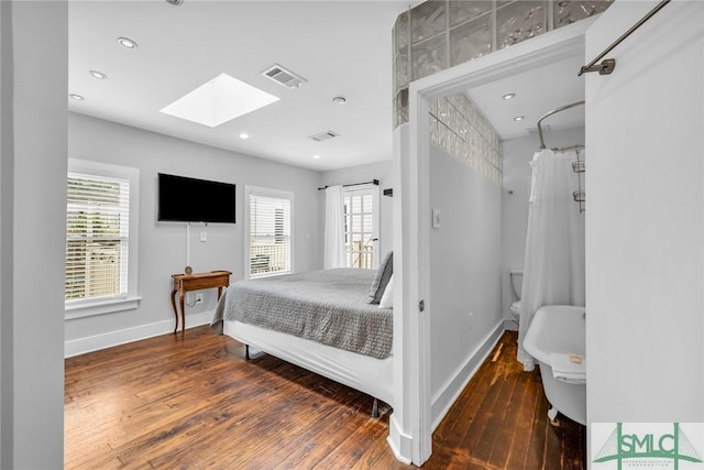 bedroom with a skylight, hardwood / wood-style flooring, baseboards, multiple windows, and recessed lighting