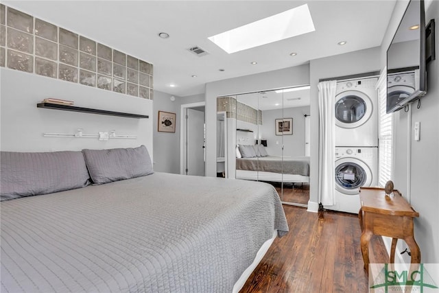 bedroom with stacked washer / drying machine, a skylight, wood finished floors, recessed lighting, and a closet