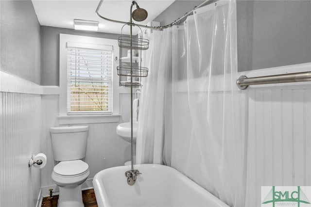 bathroom with toilet, a soaking tub, a shower with shower curtain, and wood finished floors