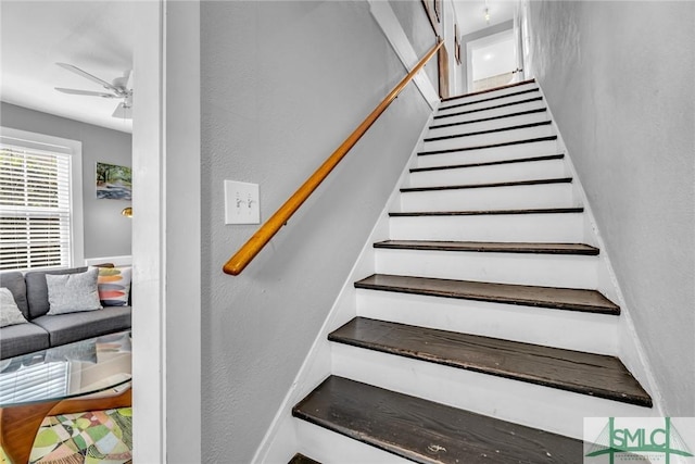 stairs featuring ceiling fan