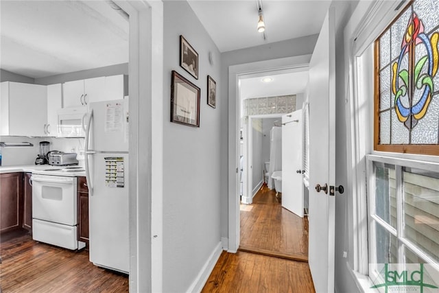 hallway with dark wood-type flooring and baseboards