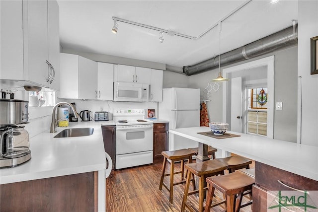 kitchen featuring white appliances, a sink, light countertops, and plenty of natural light