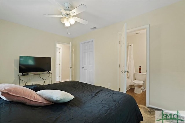 bedroom featuring baseboards, ensuite bath, ceiling fan, and wood finished floors