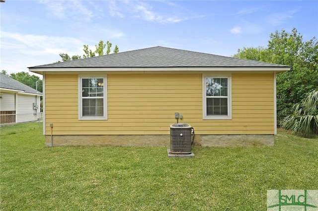 rear view of house with a lawn and central AC unit