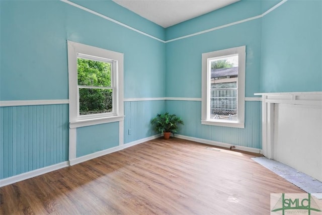 unfurnished room with wood finished floors and wainscoting