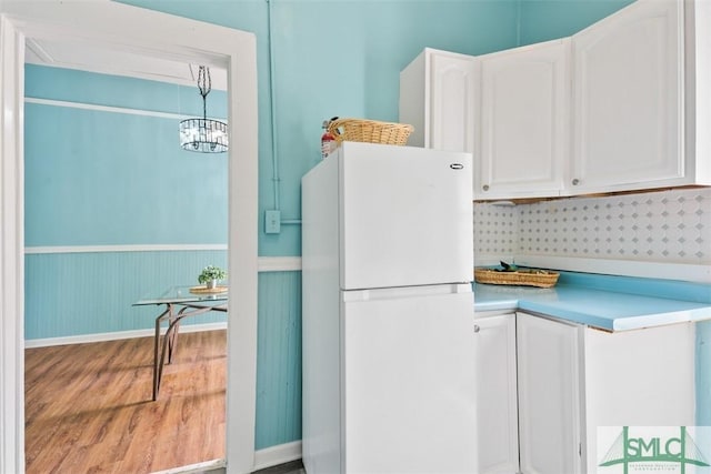 clothes washing area featuring wood finished floors, a chandelier, and a wainscoted wall