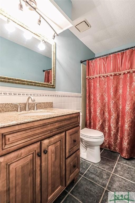 bathroom featuring toilet, vanity, tile patterned floors, tile walls, and curtained shower