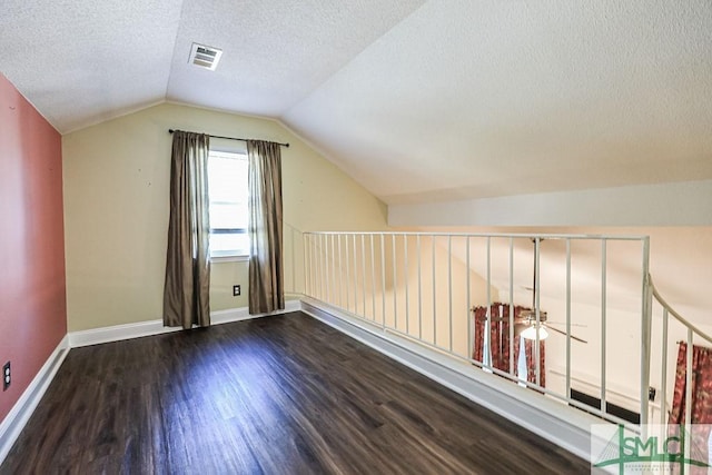 additional living space featuring a textured ceiling, wood finished floors, a ceiling fan, lofted ceiling, and baseboards