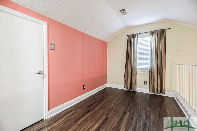 bonus room featuring wood finished floors, vaulted ceiling, baseboards, and a textured ceiling