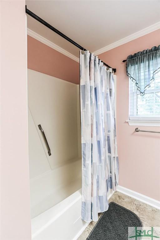 bathroom with ornamental molding, shower / bath combo with shower curtain, and baseboards