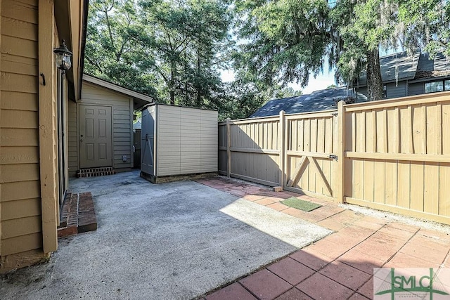 view of patio / terrace with a gate, fence, and a storage shed