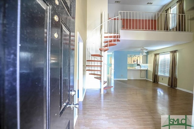 entryway with a high ceiling, stairs, wood finished floors, baseboards, and ceiling fan