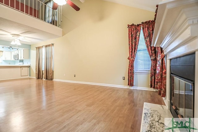 unfurnished living room with ceiling fan, light wood finished floors, and plenty of natural light