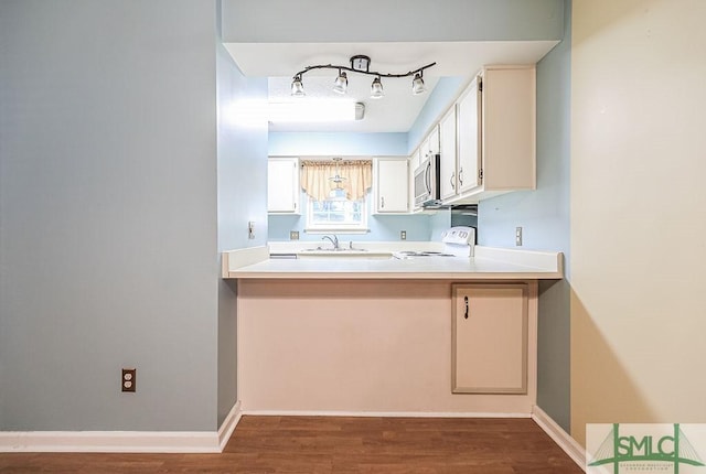 kitchen with stove, stainless steel microwave, a sink, wood finished floors, and light countertops