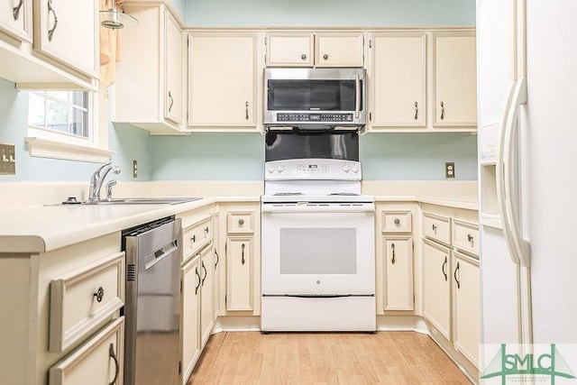 kitchen with stainless steel appliances, light countertops, a sink, light wood-type flooring, and cream cabinetry