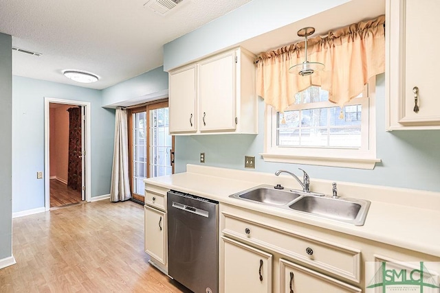 kitchen featuring stainless steel dishwasher, a sink, light countertops, light wood-style flooring, and baseboards