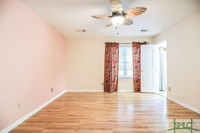unfurnished room featuring light wood-style floors, a ceiling fan, baseboards, and a textured ceiling