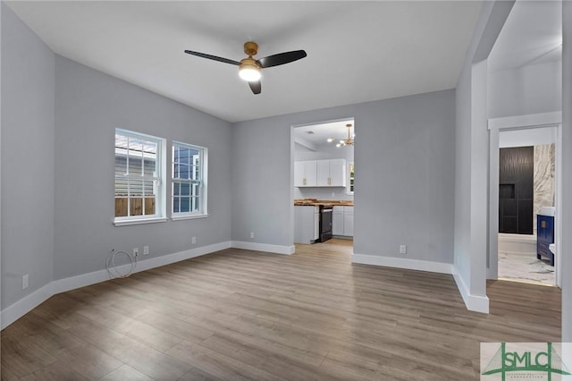 3205 Burroughs St, Savannah, GA 31405 - unfurnished living room with light wood-style flooring, a ceiling fan, baseboards, and a chandelier