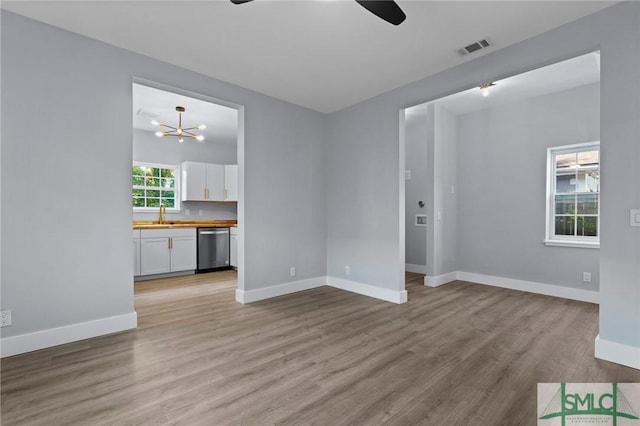 3205 Burroughs St, Savannah, GA 31405 - unfurnished living room featuring ceiling fan, light wood-style flooring, baseboards, a sink, and a chandelier
