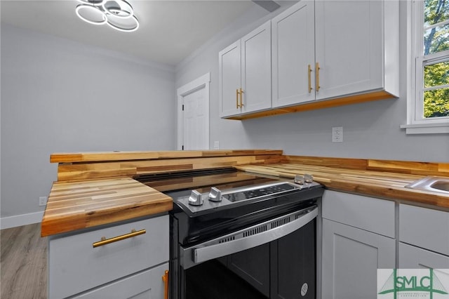 3205 Burroughs St, Savannah, GA 31405 - kitchen featuring butcher block counters, electric stove, wood finished floors, and white cabinets