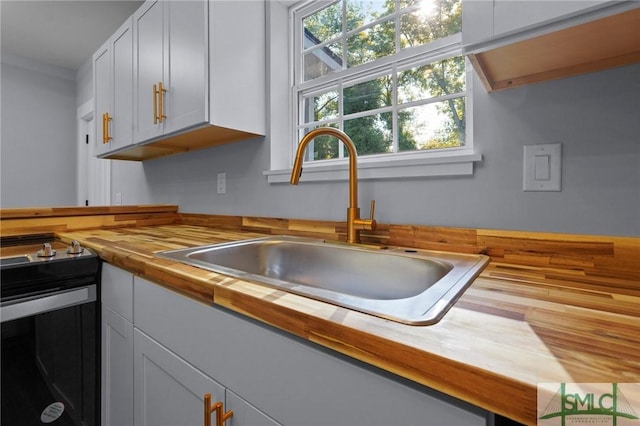 3205 Burroughs St, Savannah, GA 31405 - kitchen with butcher block countertops, a sink, range with electric stovetop, and white cabinets