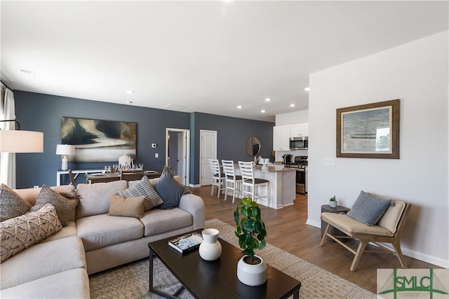 living room with wood finished floors, recessed lighting, and baseboards