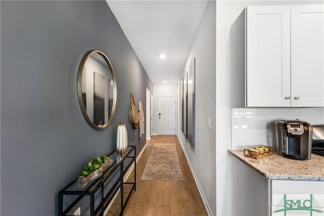 corridor with wood finished floors, baseboards, and recessed lighting