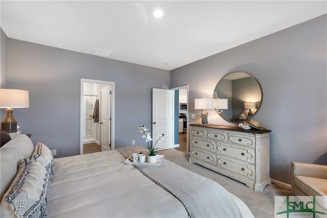 bedroom with light colored carpet, baseboards, and connected bathroom