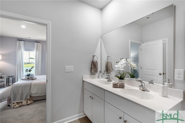 full bathroom featuring double vanity, baseboards, and ensuite bathroom
