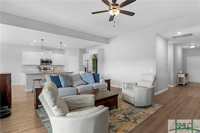 living area with a ceiling fan, wood finished floors, baseboards, and recessed lighting