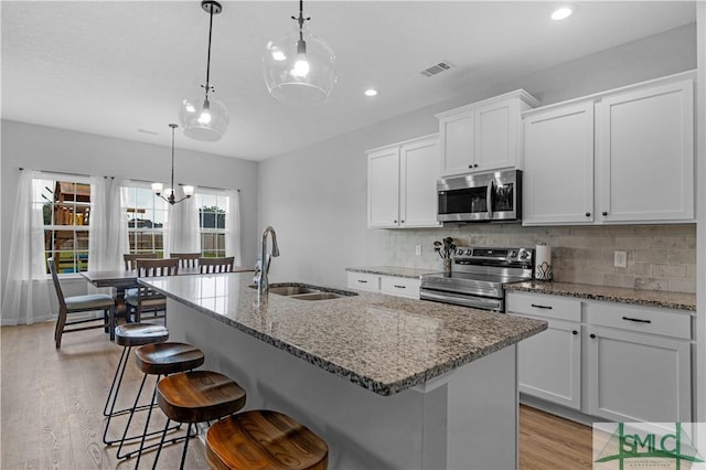 kitchen with stainless steel appliances, a sink, light wood-style flooring, tasteful backsplash, and recessed lighting