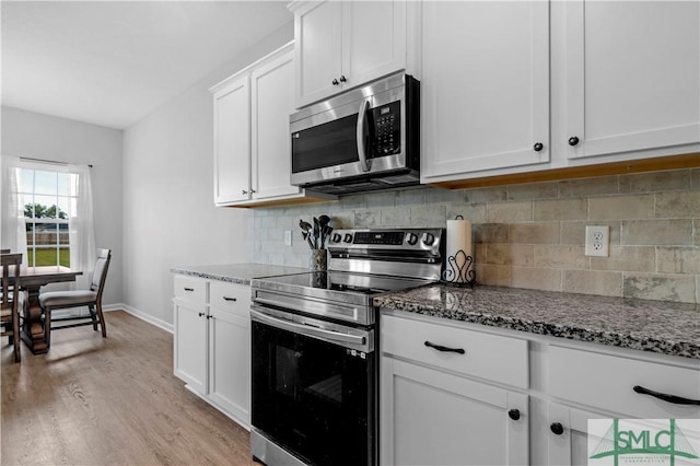 kitchen featuring appliances with stainless steel finishes, light wood-type flooring, and dark stone counters