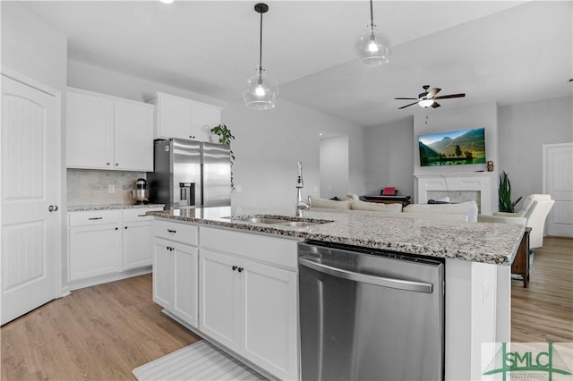 kitchen with appliances with stainless steel finishes, a sink, light wood-style flooring, and ceiling fan