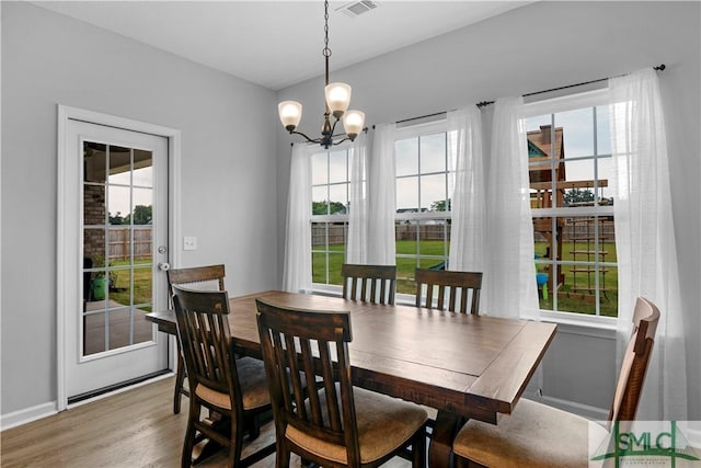 dining room with a chandelier, plenty of natural light, wood finished floors, and baseboards