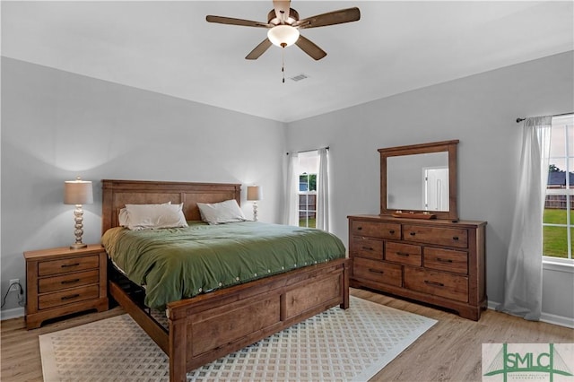 bedroom with light wood finished floors, baseboards, and a ceiling fan
