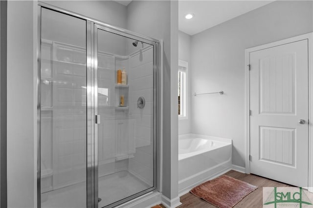 full bath with wood finished floors, a shower stall, a garden tub, and baseboards