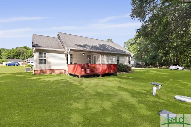 rear view of property with a deck, a yard, and roof with shingles
