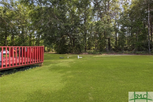 view of green lawn with a deck and view of scattered trees