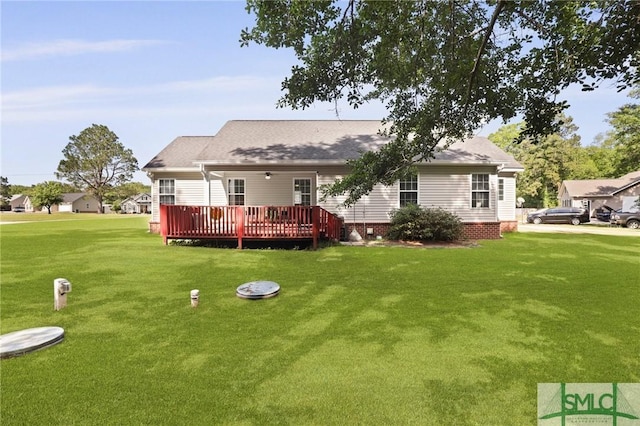rear view of property with a wooden deck, a lawn, and roof with shingles