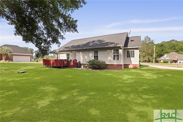 rear view of property featuring a lawn, a deck, and roof with shingles