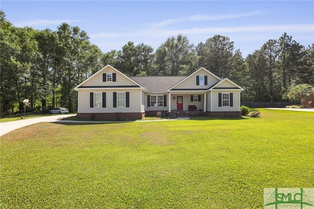 view of front of house featuring a porch, a front yard, driveway, and view of wooded area