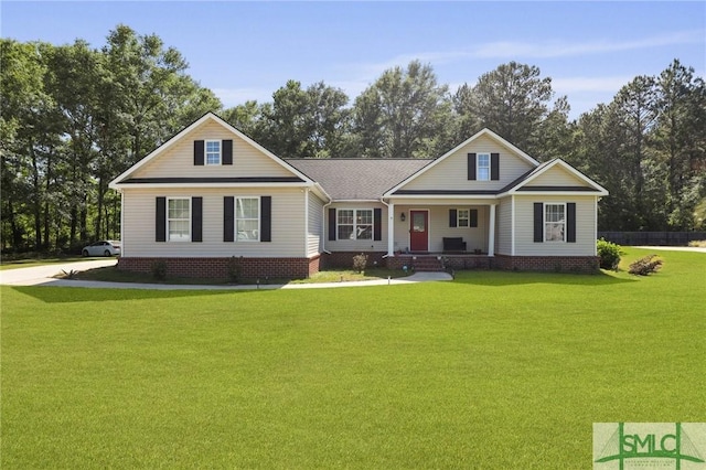 view of front of home featuring a porch, a front yard, and view of wooded area