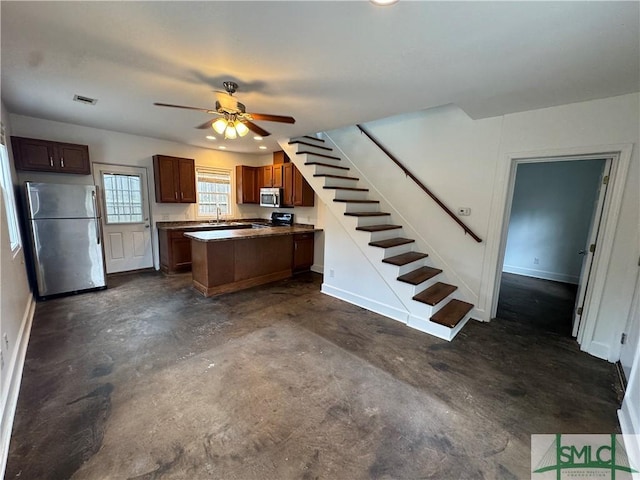 1305 E Anderson St, Savannah, GA 31404 - kitchen featuring stainless steel appliances, a peninsula, dark countertops, unfinished concrete flooring, and a ceiling fan